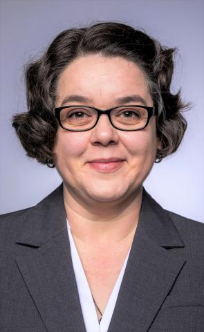 Photo of Associate Professor Csoba DeHass - woman with short brown curly hair and glasses.
